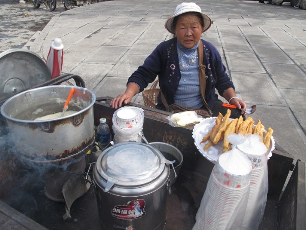 Signora a Xizhou che vende frittelle dalla mattina alla sera sulla strada